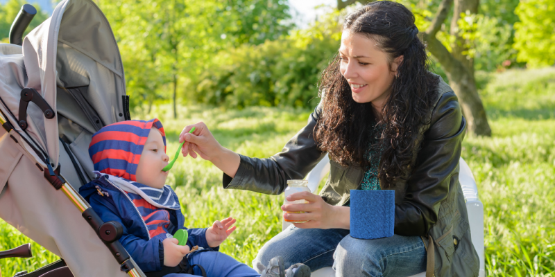 Baby wird unterwegs aus dem Emeal Breibehälter gefüttert